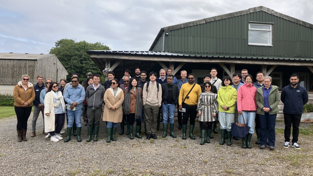 A group of international buyers standing outside a farm building